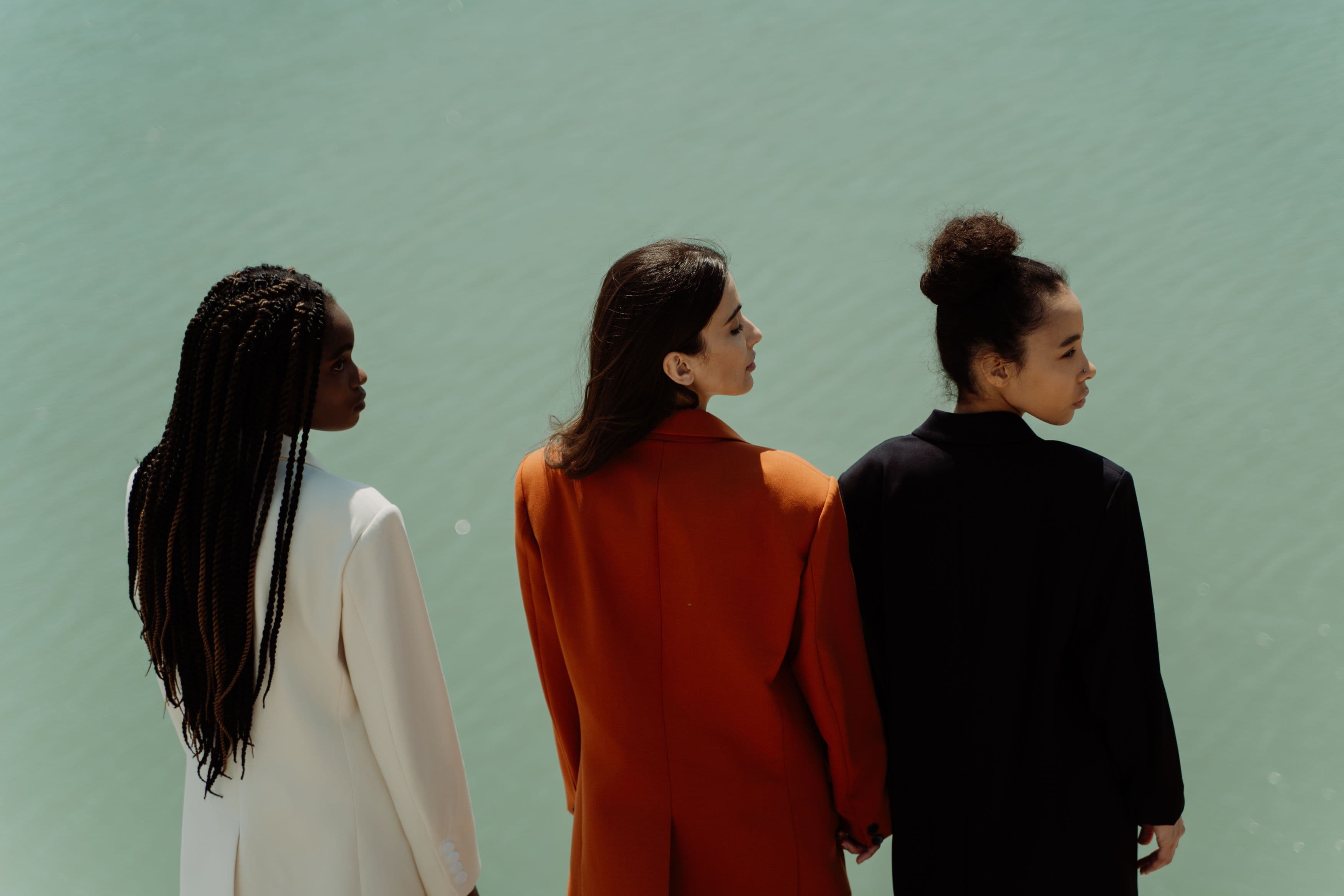 Tres mujeres usando blazers junto al agua